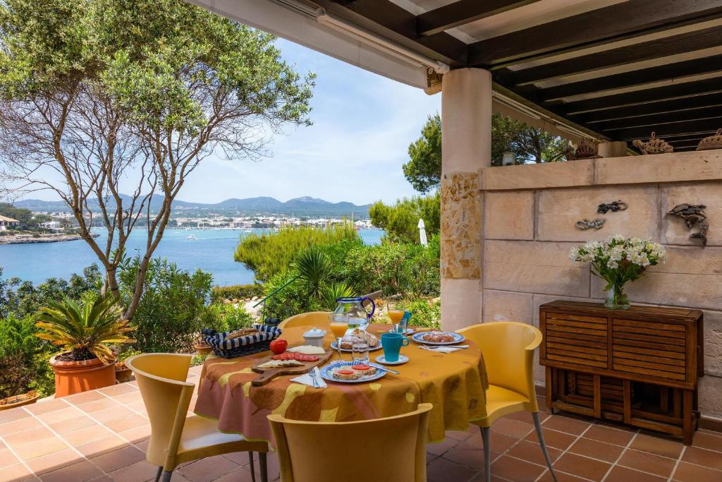 a table and chairs on a patio with a view of the water at Casa Vacacional Es Niu in Portocolom