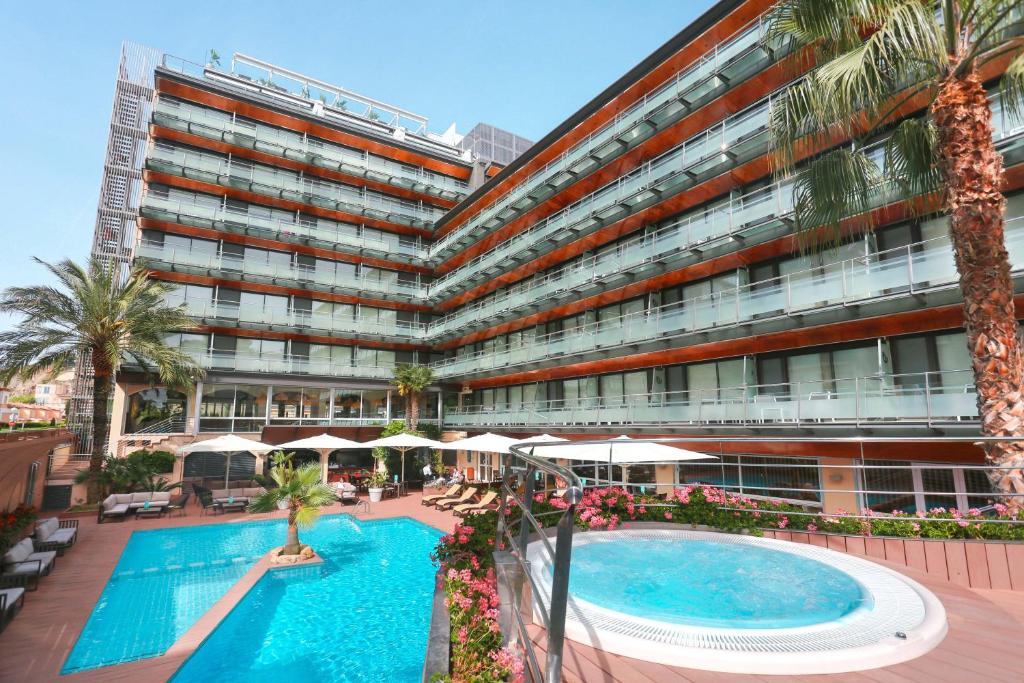 un gran edificio con una piscina frente a él en Hotel Kaktus Playa - Adults Recommended, en Calella