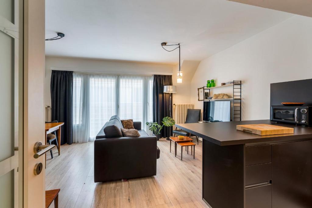 een keuken en een woonkamer met een bank en een tafel bij Retro woning te centrum Oostende, 5min van de kust in Oostende