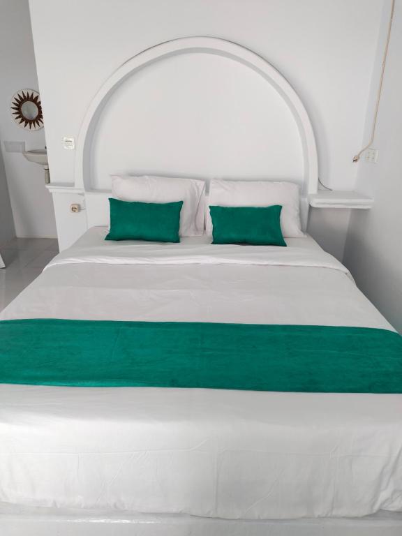 Una cama blanca con dos almohadas verdes. en Casa di Stella, en Ngurblut