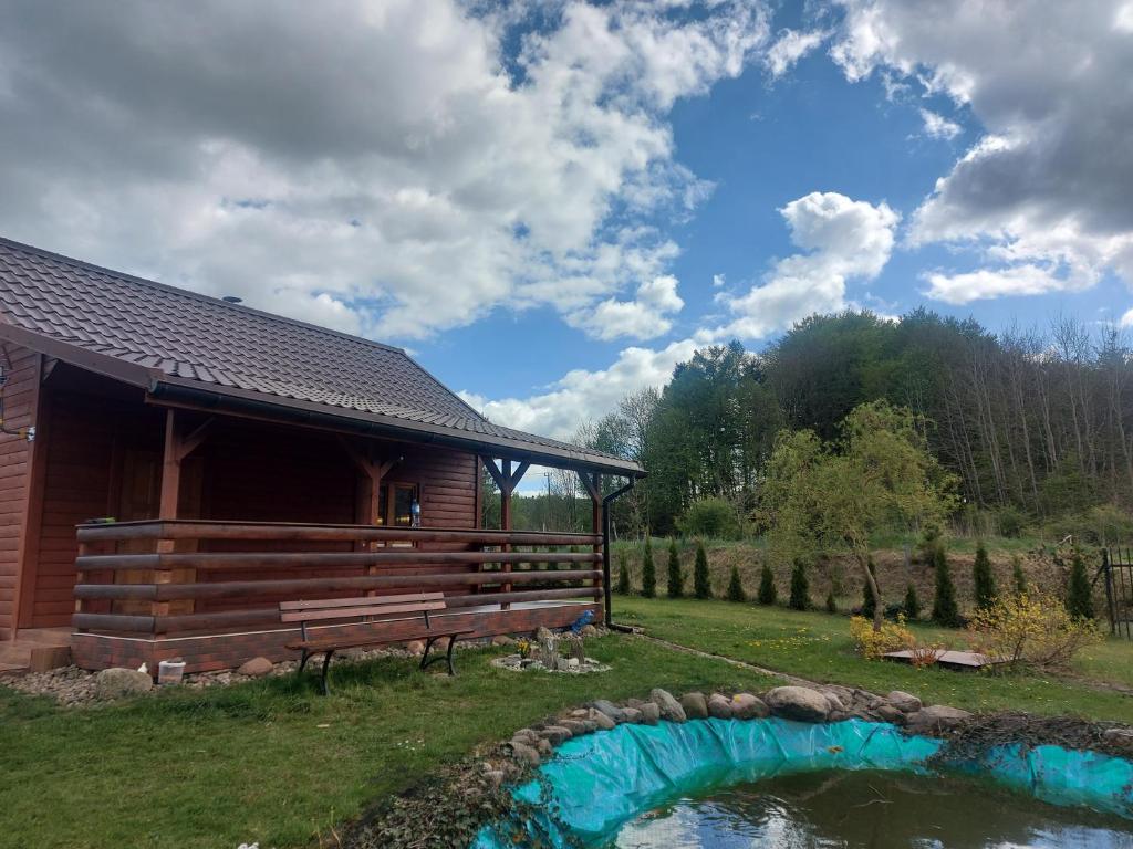 domek z bali z ławką przy stawie w obiekcie Drewniany domek Żurawi Trakt w mieście Ząbrsko Dolne