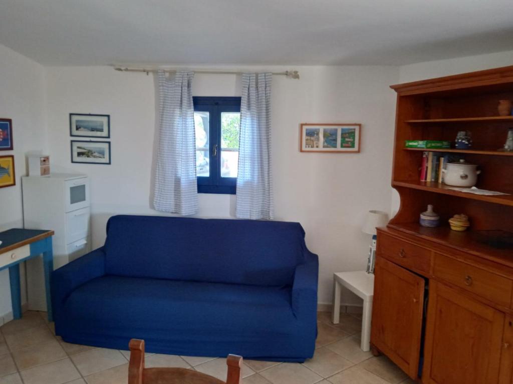 a blue chair in a living room with a window at Villa Vera trifamigliare con ingresso diretto 20 mt al mare clima wi-fi bbq in Cala Liberotto