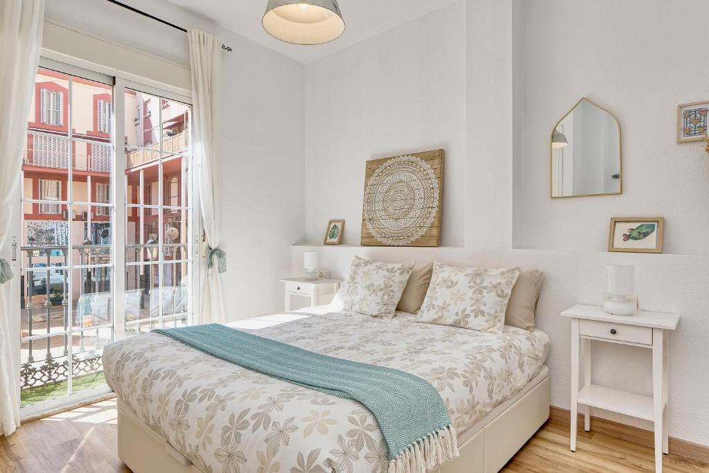 ein weißes Schlafzimmer mit einem Bett und einem Fenster in der Unterkunft Bright & Breezy MERCED in Málaga