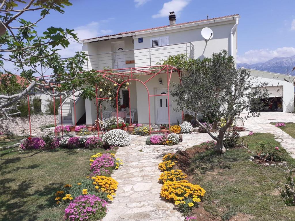 une maison avec des fleurs devant elle dans l'établissement Apartmani Vera, à Ražanac