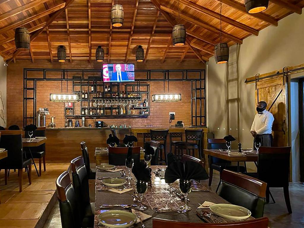 a man standing in a restaurant with tables and chairs at Bamboo Boutique Hotel in Lilongwe