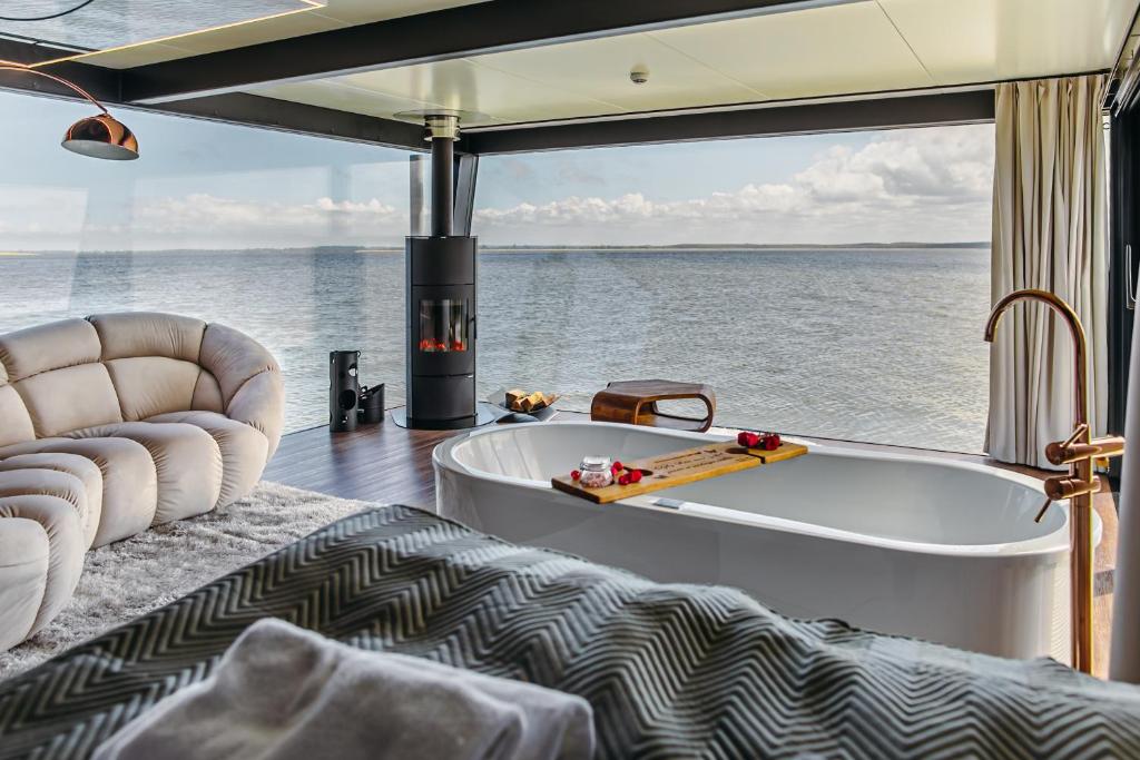 um quarto com uma banheira e vista para a água em Domki na wodzie - Grand HT Houseboats - with sauna, jacuzzi and massage chair em Mielno