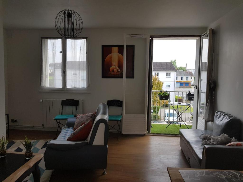 een woonkamer met 2 banken en een deur naar een patio bij Superbe appartement de 41m2 en résidence privé in Fleury-les-Aubrais