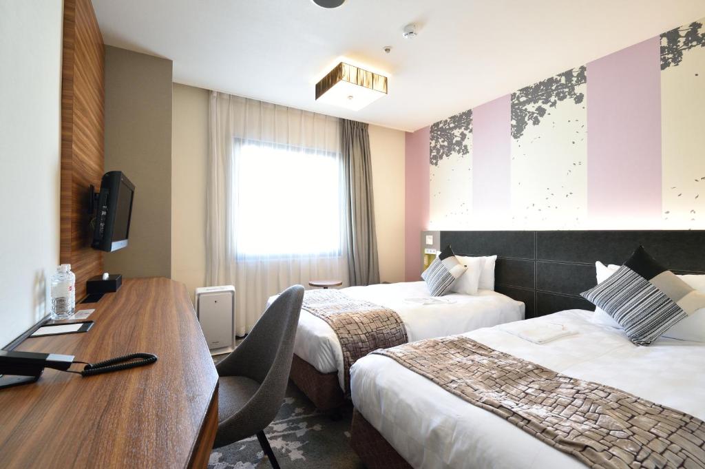 a hotel room with two beds and a desk and a table at Kichijoji Tokyu REI Hotel in Musashino