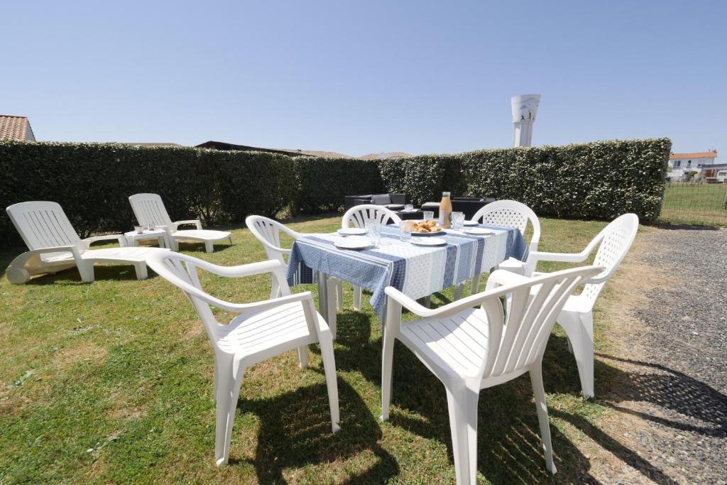 a group of white chairs sitting around a table at Une grande maison pour 10 proche de la mer in Saint-Gilles-Croix-de-Vie