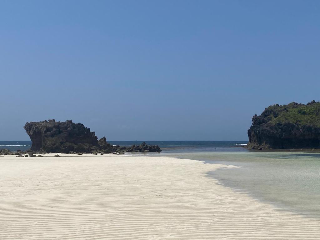 a sandy beach with rocks in the ocean at Watamu Shell House in Watamu