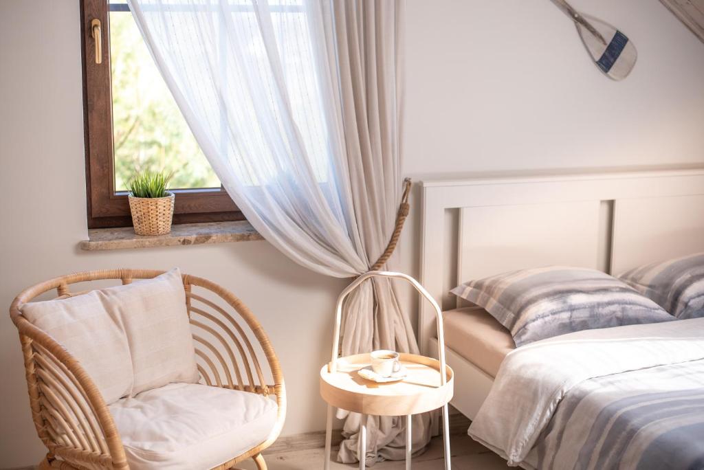 a bedroom with a bed and a chair and a table at Zielone Miejsce - w otoczeniu natury, z balią z jacuzzi opalaną drewnem in Karwia