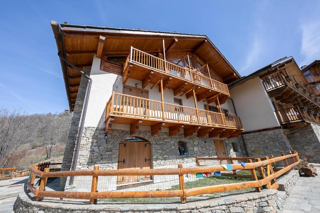 a building with a balcony and a wooden fence at Rebecca's House few steps from skiing - Happy Rentals in Bardonecchia