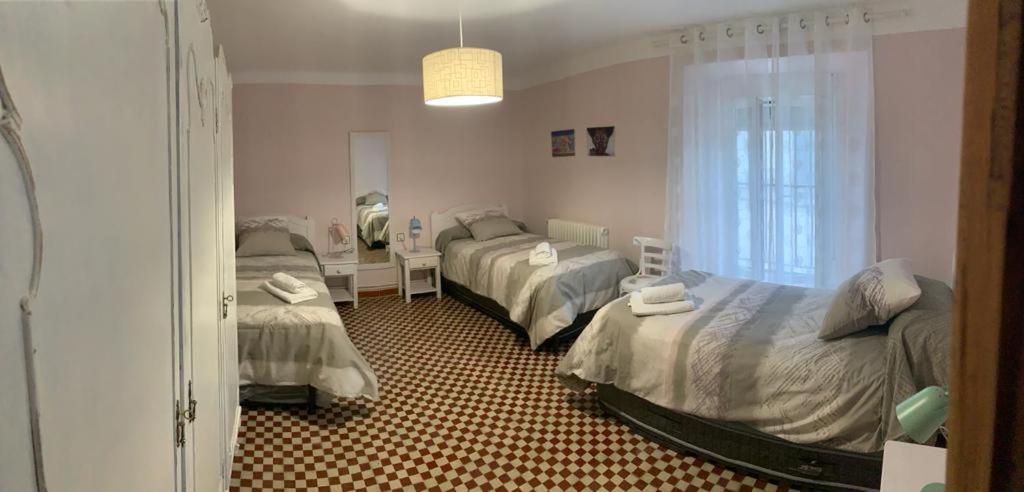 1 dormitorio con 3 camas, mesa y ventana en Casa de los Maestros, en Rágama