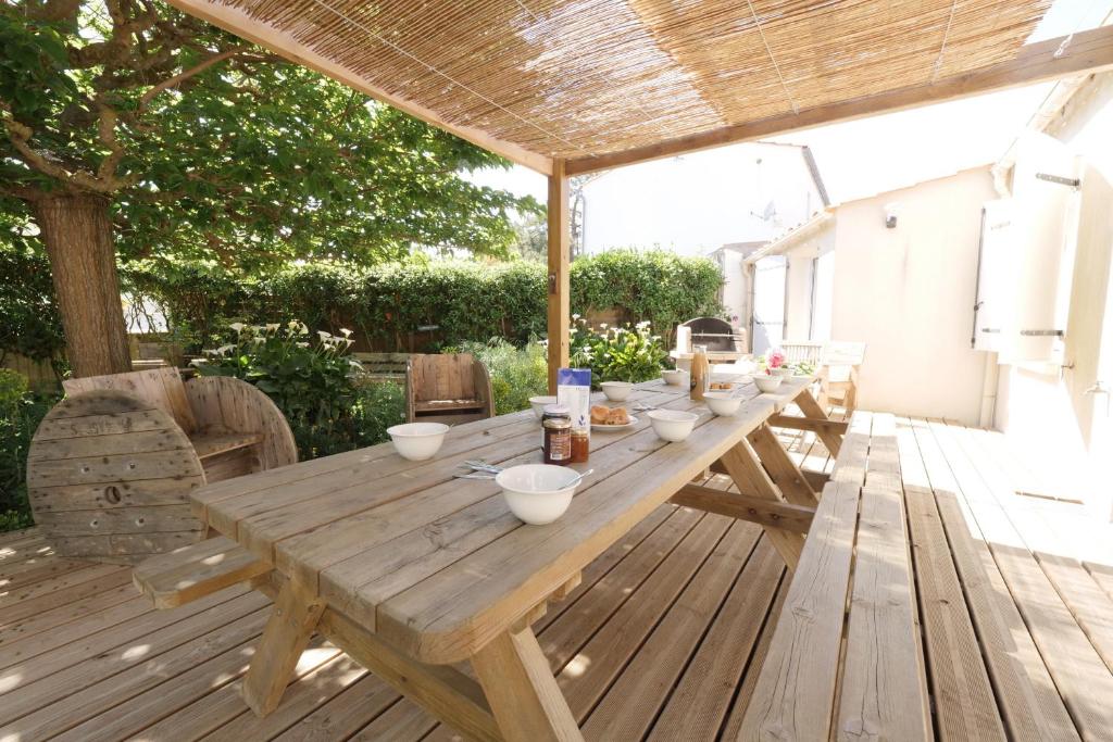 una mesa de madera con tazones de comida en una terraza en Ensemble, dans une maison avec jardin près de la mer en Brétignolles-sur-Mer