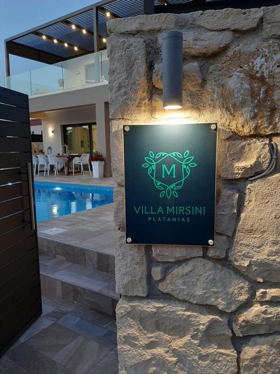 a sign for a villa in a building with a swimming pool at Platanias Villa Mirsini in Plataniás