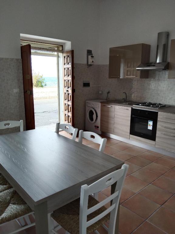 - une cuisine avec une table en bois et des chaises blanches dans l'établissement Casa di Sole, à Cariati