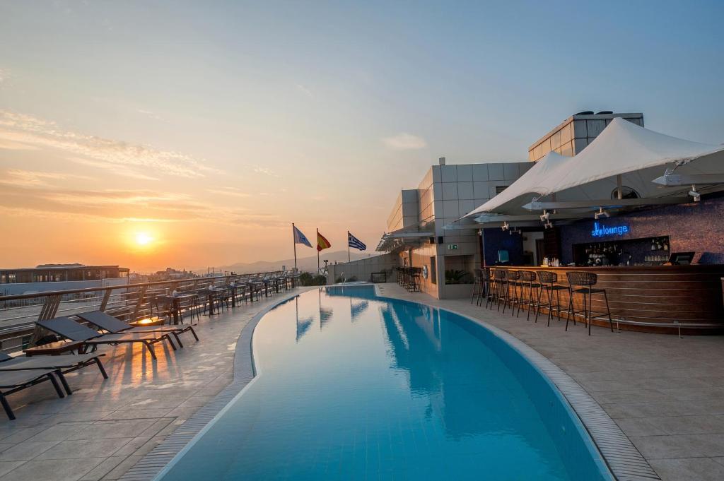 a swimming pool on top of a building with a sunset at Melia Athens in Athens