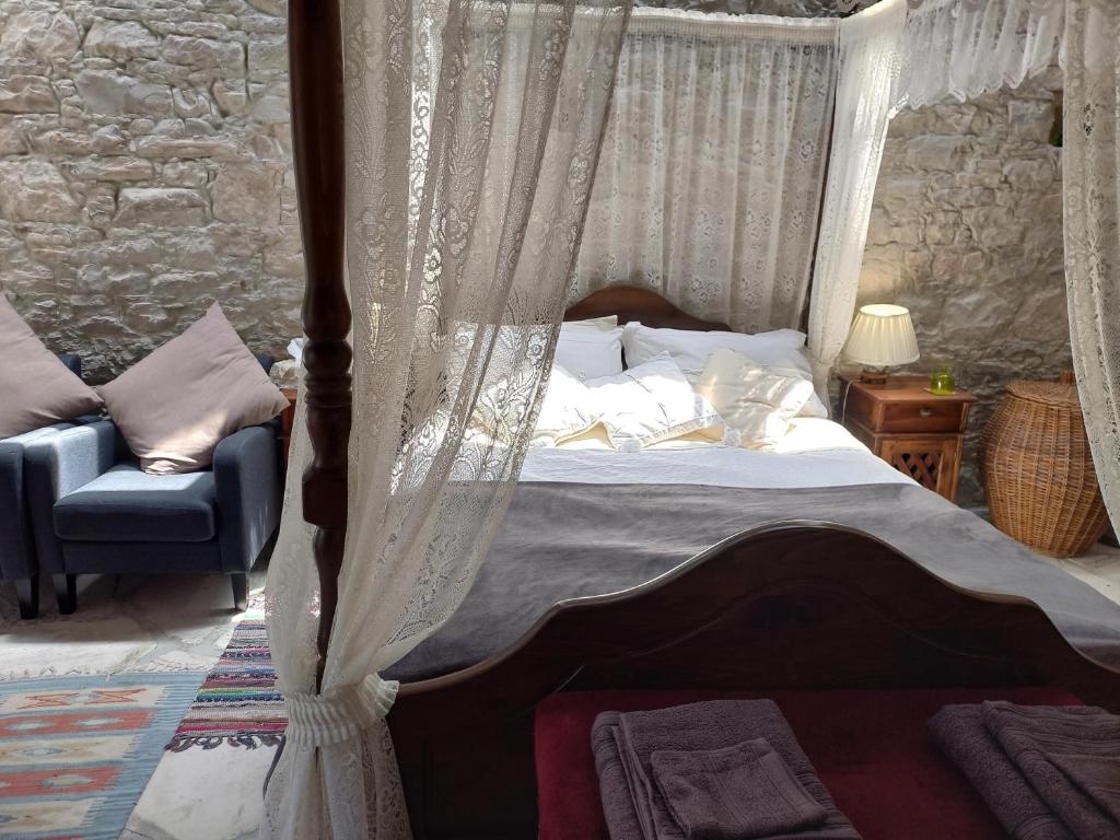 ein Schlafzimmer mit einem Himmelbett und einem Stuhl in der Unterkunft The Spidaki in Lania