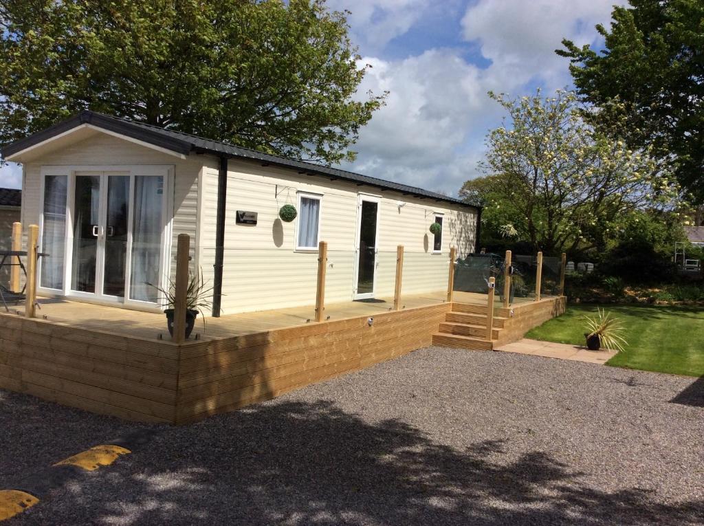 ein kleines Haus mit einer Veranda und einer Terrasse in der Unterkunft Lake District Cumbria Gilcrux Solway Firth Cabin in Wigton