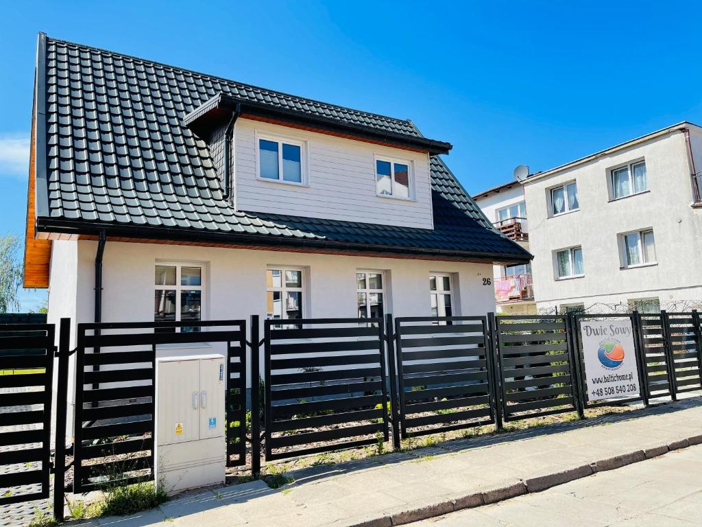 una casa con una valla negra delante de ella en Dwie Sowy by Baltic Home, en Międzyzdroje
