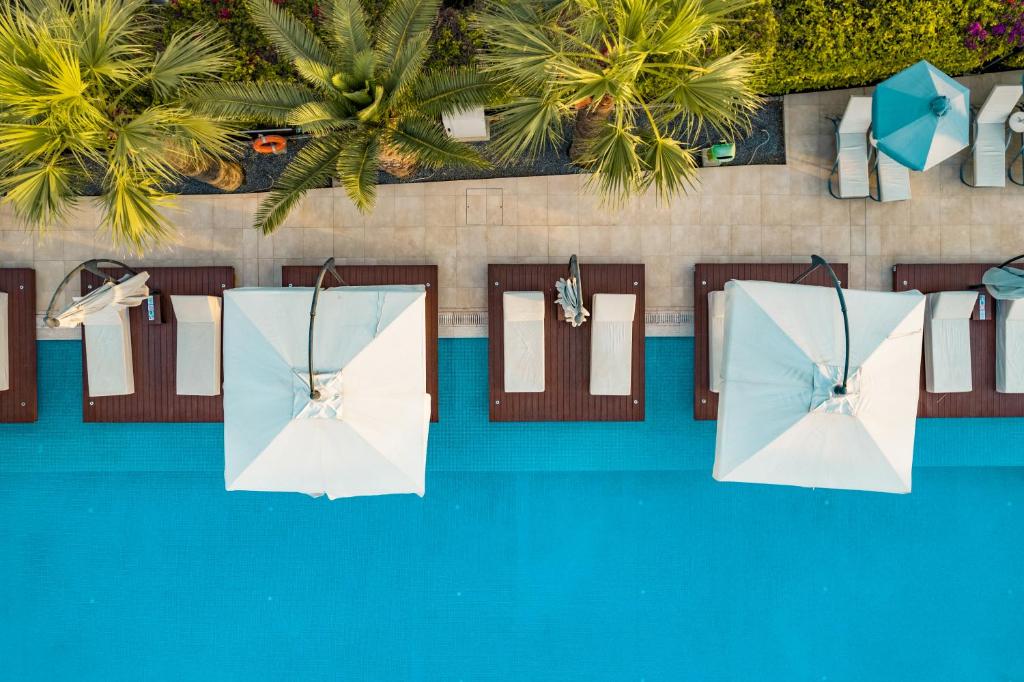 an overhead view of two white umbrellas next to a pool at Nestor Hotel in Ayia Napa