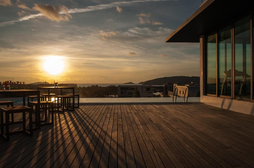 una terraza con mesa, sillas y puesta de sol en Sky Hotel, en Kota Kinabalu