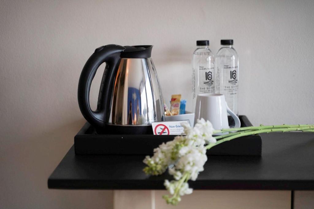 a black tea kettle and flowers on a black counter at The Sixteenth Naiyang Beach Hotel SHA Plus in Nai Yang Beach