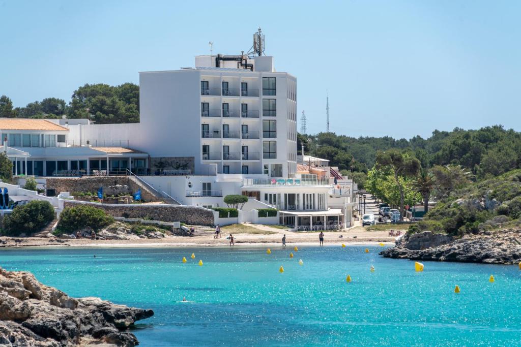 uma vista para uma praia com um edifício ao fundo em Hotel Playa Santandria Adults Only em Cala Santandria