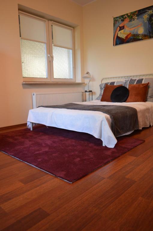 a bedroom with a large bed with a red rug at Apartament przy Koniu Trojańskim in Luboń