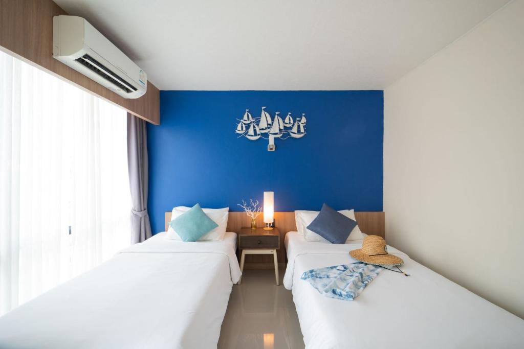 two beds in a room with a blue wall at The Sixteenth Naiyang Beach Hotel SHA Plus in Nai Yang Beach
