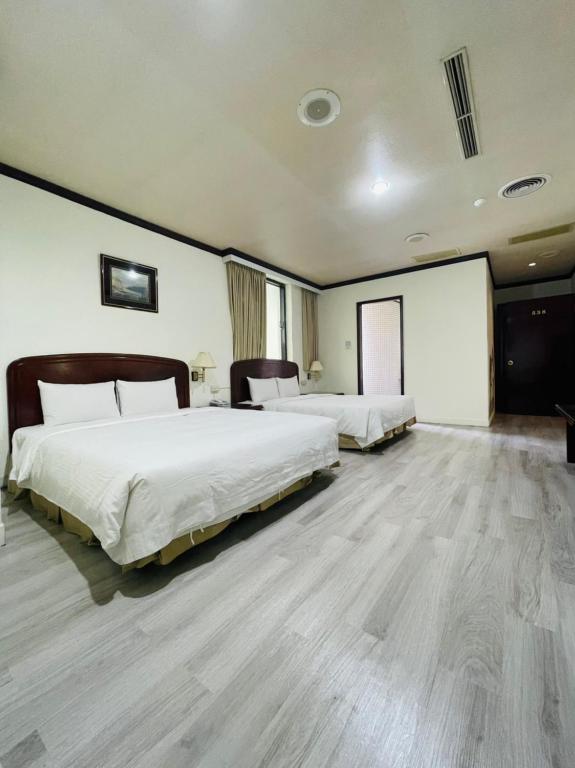 two beds in a large room with wooden floors at Abbo Hotel in Tainan