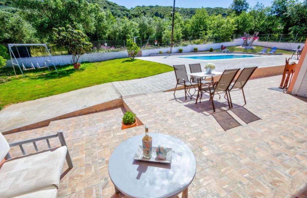 eine Terrasse mit einem Tisch, Stühlen und einem Pool in der Unterkunft Villazia Exclusive Estate in Episkopianá