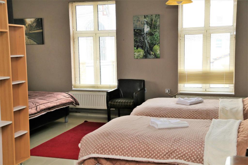 a room with two beds and a chair and windows at Vilas Ambasador Bratin Dol in Bitola