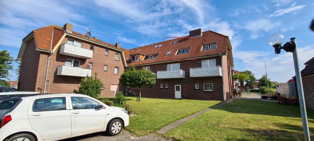 een witte auto geparkeerd voor een bakstenen gebouw bij Modernisierte Ferienwohnung Friedrichskoog - Spitze, gegenüber Mutter-Kind-Klinik in Friedrichskoog