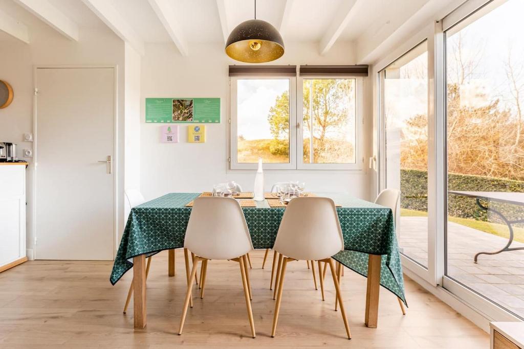 une salle à manger avec une table et des chaises vertes dans l'établissement West Green - Maison entre Dunes et Lac, à Le Touquet-Paris-Plage