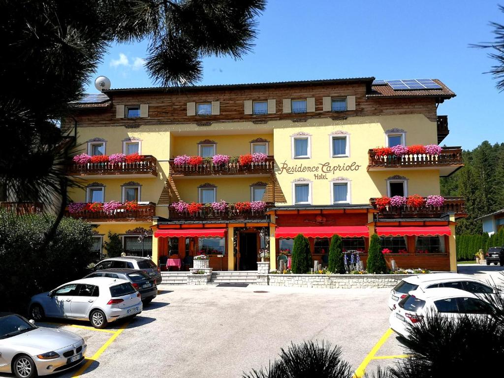 een groot gebouw met auto's geparkeerd op een parkeerplaats bij Residence Capriolo in Lavarone