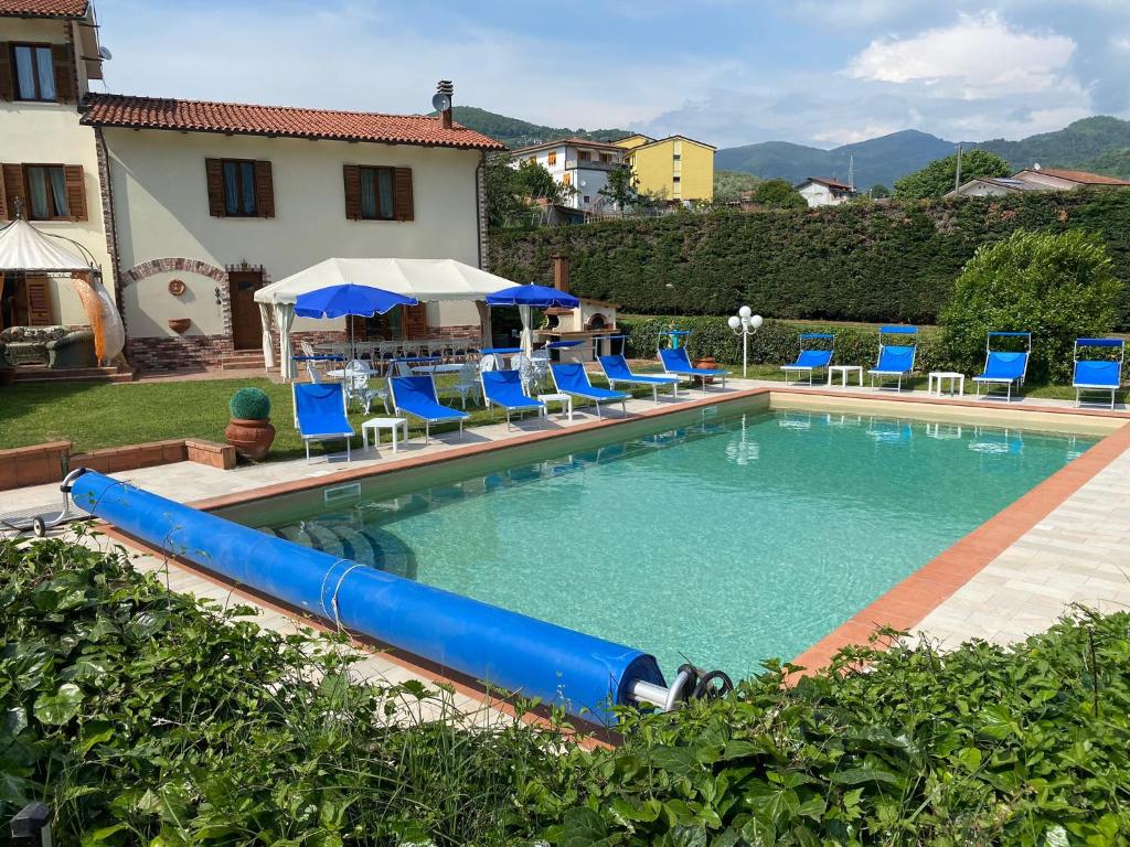 a pool with blue chairs and a water slide at Villa con piscina tra Versilia e Cinque Terre in Luni