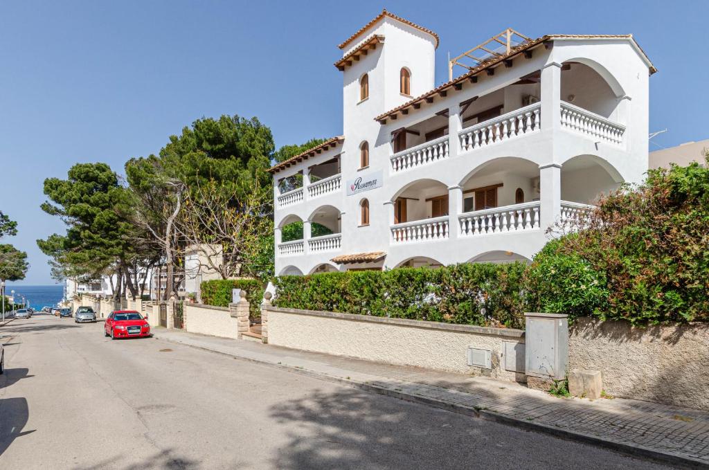 ein rotes Auto, das vor einem weißen Gebäude parkt in der Unterkunft Rosamar Holidays Apartments in Cala Ratjada