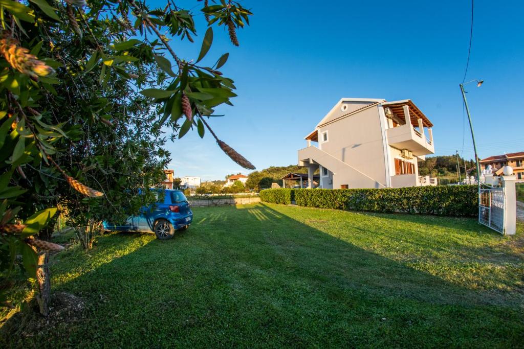 ein Auto, das auf einem Hof neben einem Haus parkt in der Unterkunft George Apartments in Arillas