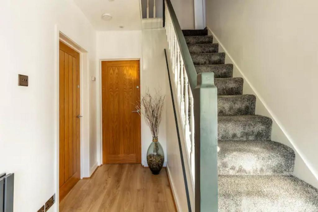 a hallway with a staircase with a vase next to a door at Camaraderie Guest House in York