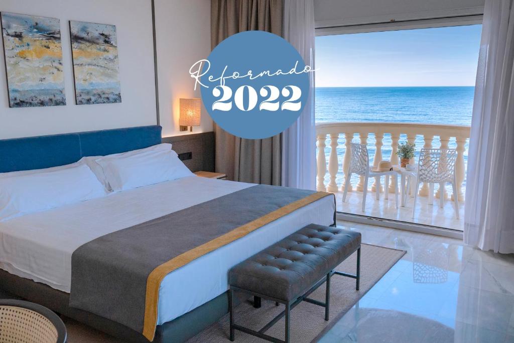 URH Sitges Playa في سيتجيس: غرفة نوم مع سرير وإطلالة على المحيط