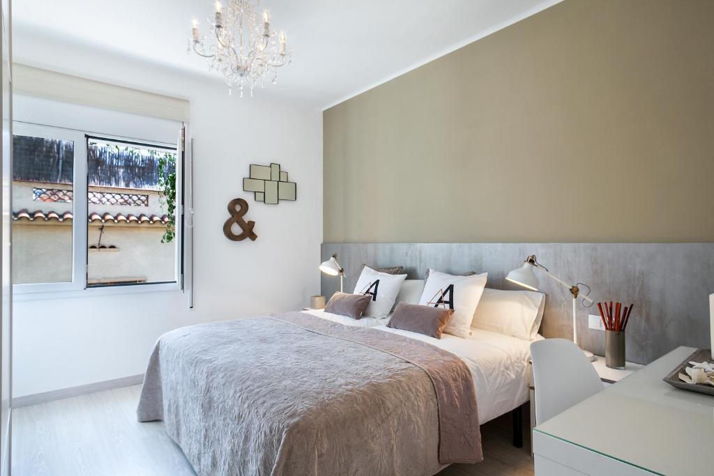 a white bedroom with a bed and a chandelier at Charming & Quiet Park Guell Apartment in Barcelona