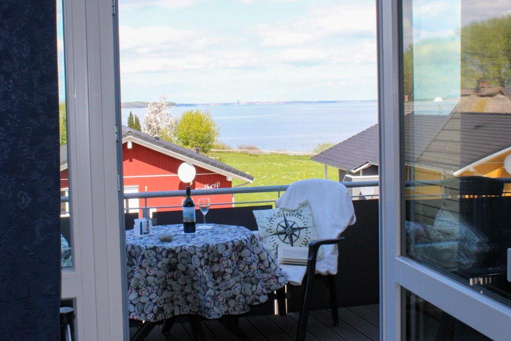 a table on a balcony with a view of the water at Fördeloft 2 in Nieby
