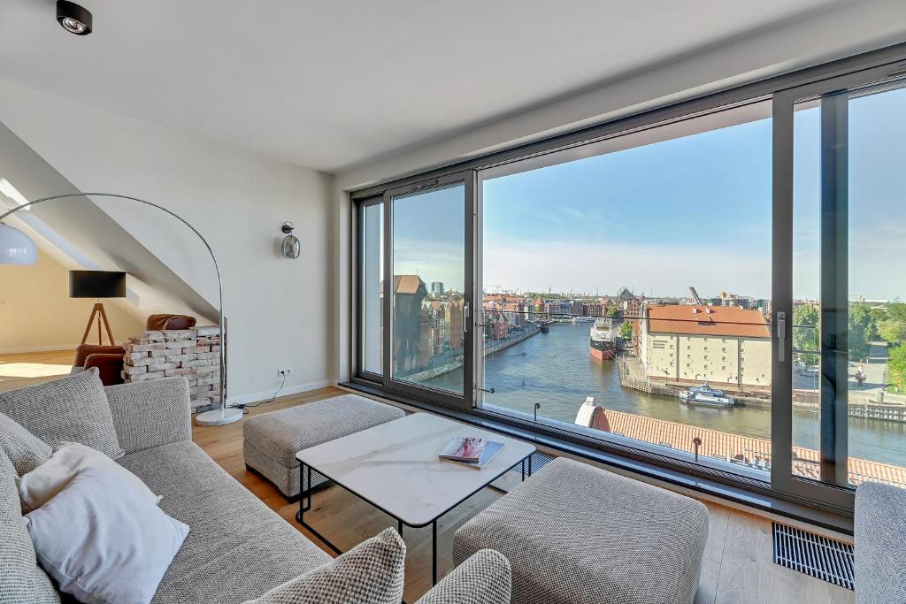 a living room with a large window overlooking a river at Granaria Comfort Apartments in Gdańsk