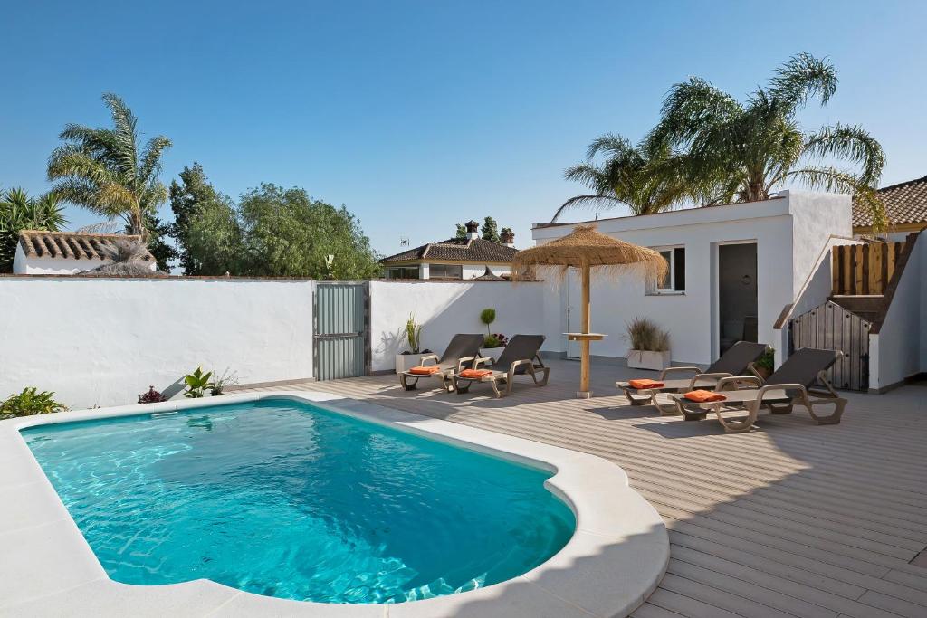 uma piscina com cadeiras e um guarda-sol num pátio em Casa Villanueva 1 -sólo Familias em Conil de la Frontera