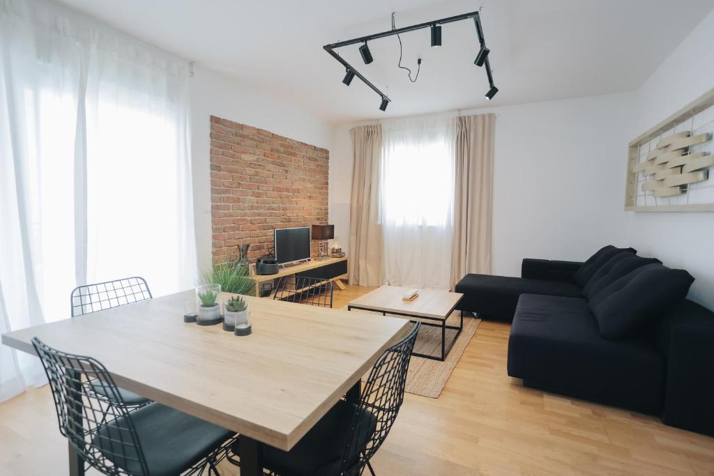 ein Wohnzimmer mit einem Tisch und einem schwarzen Sofa in der Unterkunft Apartman Tema in Podstrana