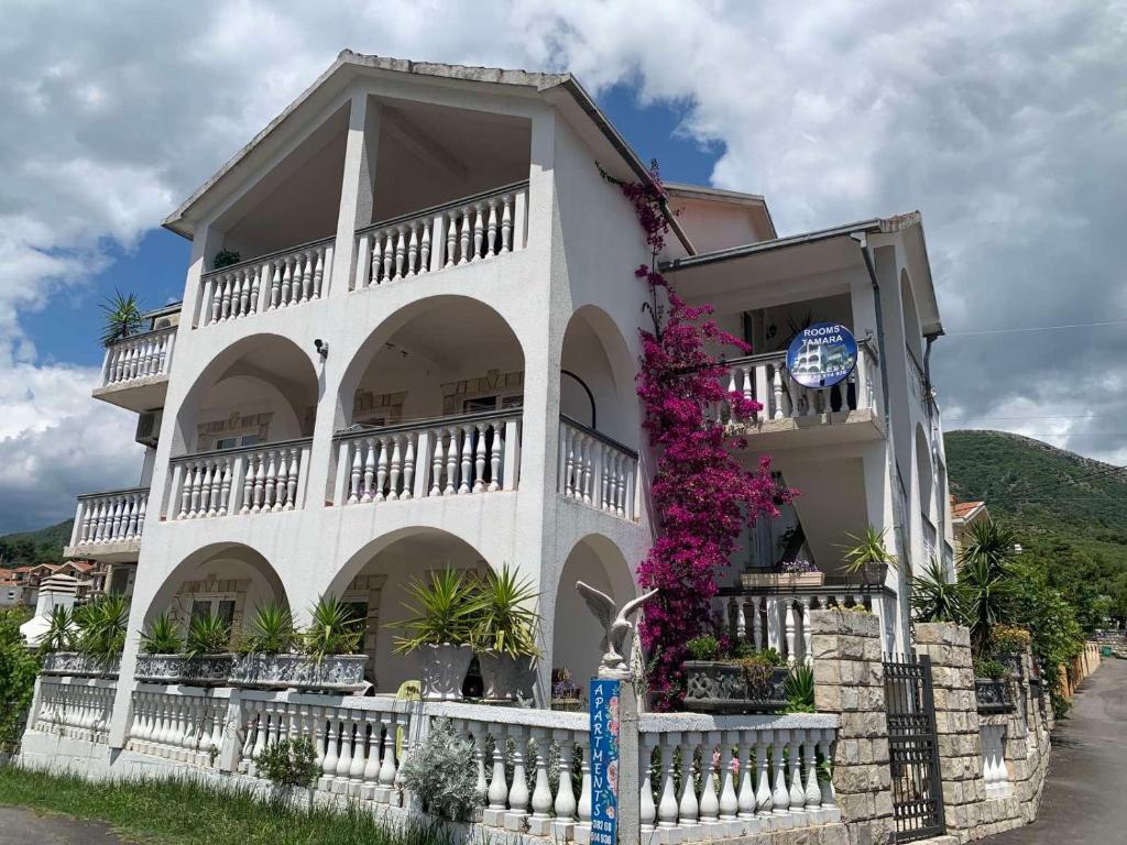un edificio bianco con dei fiori sul lato di Apartmani Tamara a Tivat