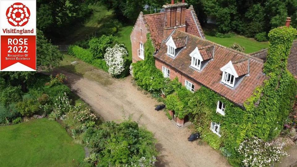 an aerial view of a large house with ivy at Carrick's at Castle Farm in Swanton Morley