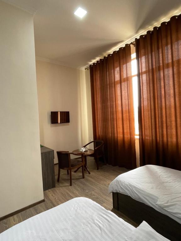 Pokój hotelowy z 2 łóżkami, krzesłem i biurkiem w obiekcie Rudaki Hotel in Panjakent w mieście Panjakent