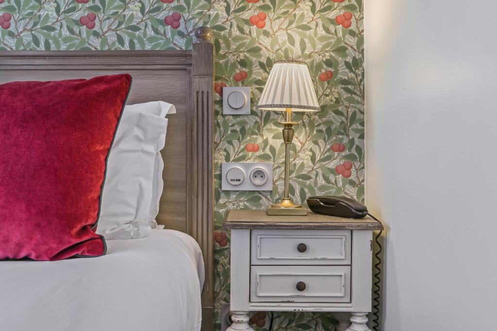 een slaapkamer met een bed en een lamp op een nachtkastje bij Hôtel de Sèvres in Parijs